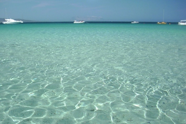 A clear turquoise sea with boats in the distance.