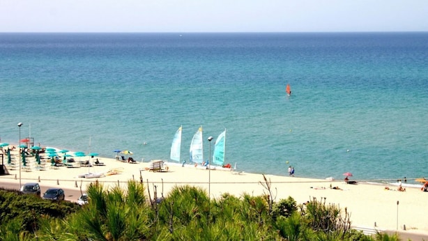 A beach with a clear view of the sea, several sailboats, and beach umbrellas. - Badus Two-room apartment, WIFI, A.C, swimming pool (Badesi)