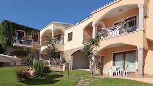 A multi-story building with balconies, outdoor seating, and a stone archway. - Badus Two-room apartment, WIFI, A.C, swimming pool (Badesi)