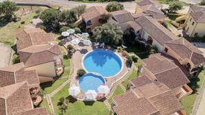 A residential complex with multiple buildings, a central swimming pool, and outdoor seating areas. - Badus Two-room apartment, WIFI, A.C, swimming pool (Badesi)