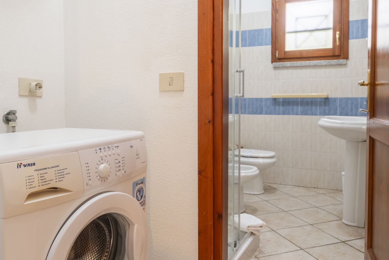 Ein kleines Badezimmer mit Waschmaschine, Toilette und Waschbecken.
