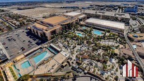 An aerial view of a hotel complex with multiple buildings, parking areas, and a large swimming pool surrounded by palm trees. - MGM Signature-28-602 1Br 2Ba Balcony Jacuzzi Suite (Las Vegas)