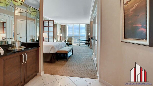 Habitación de hotel con una cama grande, un escritorio, una silla, una ventana con vistas y una zona de cocina con armarios y encimera.