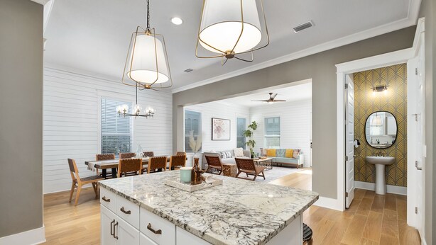 A spacious kitchen with a marble island, wooden cabinets, and pendant lighting. - Amazing Beach house Steps from 30a | Golf Cart | Beach, Pool & Lake access! (Inlet Beach)