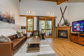 A living room with a leather sofa, a coffee table, a fireplace, and a television displaying streaming services.