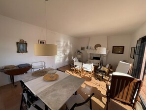 En rummelig opholdsstue med spisebord, stole, sofa og pejs.
