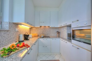 Departamento familiar, 2 habitaciones, refrigerador y microondas (Residenza Parco Carona) | Cocina privada | Refrigerador, microondas, horno y parrilla de estufa