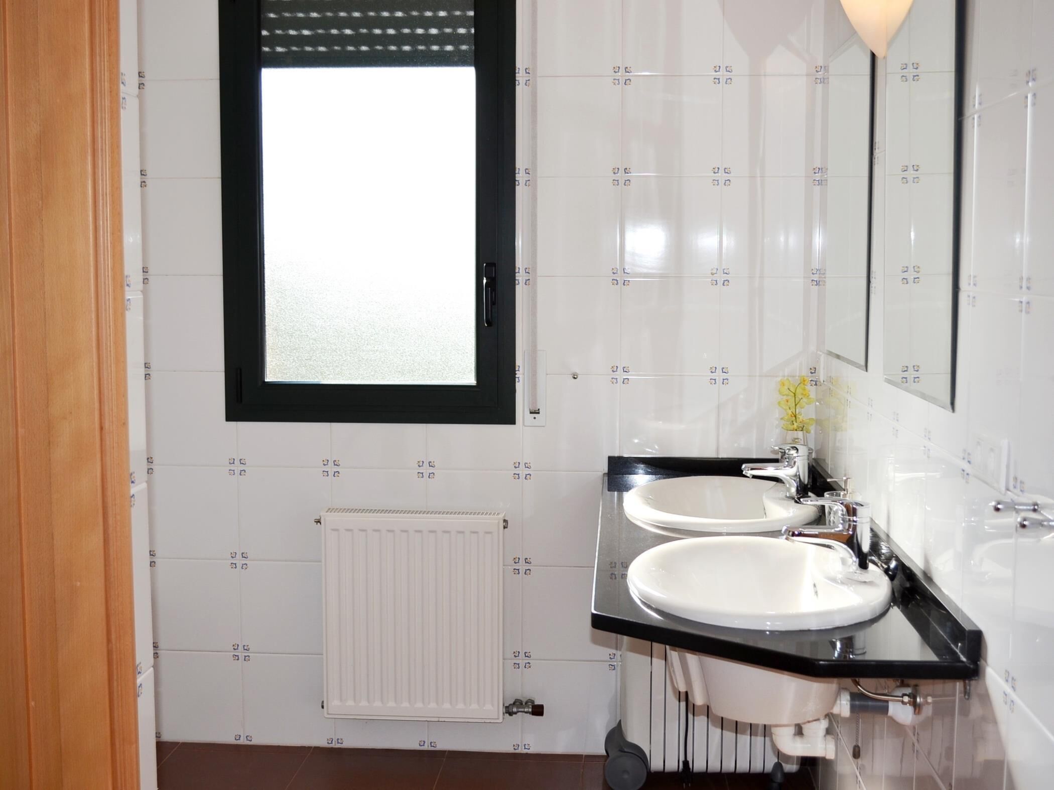 Un baño moderno con dos lavamanos, un espejo y una ventana.