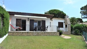 Ein Haus mit Steinverkleidung, einem Balkon mit Sitzgelegenheiten und einem kleinen Garten.