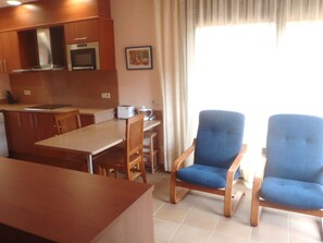 A kitchen with wooden cabinets, a dining table, and two blue chairs. - Apartment: L´Estudi, Begur, Costa Brava (begur)