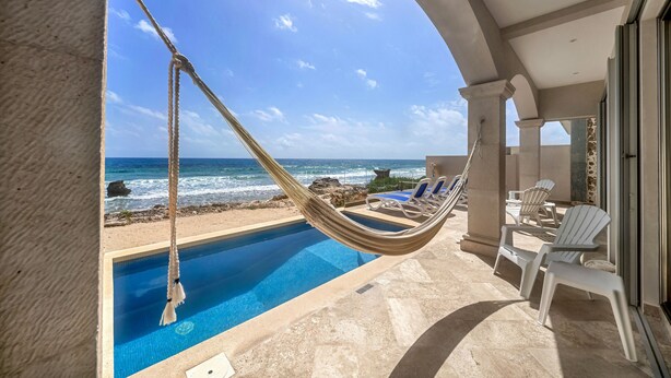 A poolside area with a hammock, lounge chairs, and a view of the ocean. - Steps to Sand- Serene Beachfront Getaway in Isla Mujeres, Mexico. (Isla Mujeres)