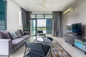 Un salon moderne comprenant un canapé, des fauteuils, une table basse, un téléviseur et un balcon avec vue.