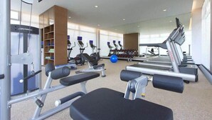 Un gimnasio con diversos equipos de ejercicio, incluyendo cintas de correr, máquinas de pesas y pesas libres.