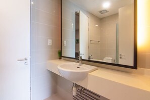 Een moderne badkamer met een witte wasbak, een grote spiegel en een douchehoek.