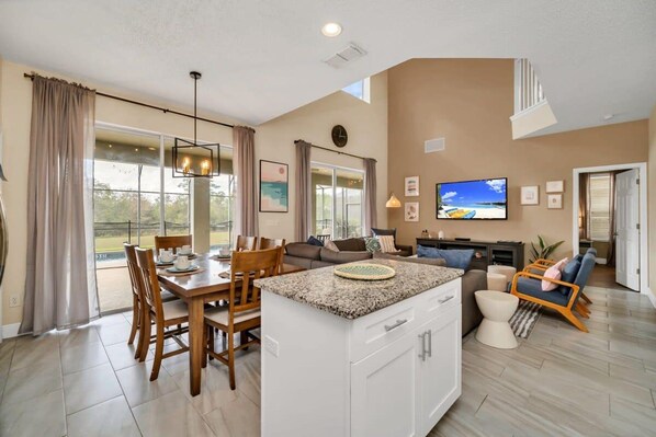 A spacious living area with a dining table, kitchen island, and seating arrangements.