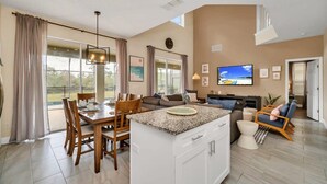 A spacious living area with a dining table, a kitchen island, and a seating area with a sofa and chairs. - Southwest facing pool! 5 Miles from Disney. (Kissimmee)