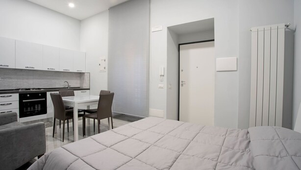 Ein kompaktes Hotelzimmer mit Bett, einer Küchenzeile, einem Essbereich und einem Badezimmer.
