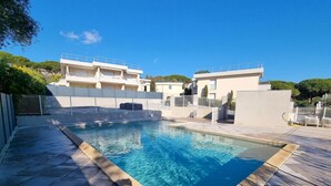 A rectangular swimming pool with a wooden deck edge, surrounded by a white fence and a white wall. - Apt With Pool   Magnificent Sea View, 80m To Beach (Sainte-Maxime)