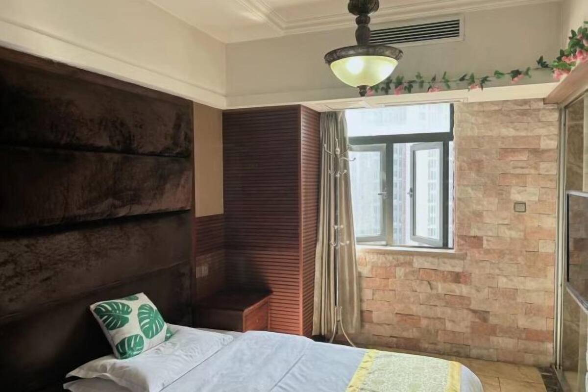 A bedroom with a bed, a headboard, a window, and a stone wall.