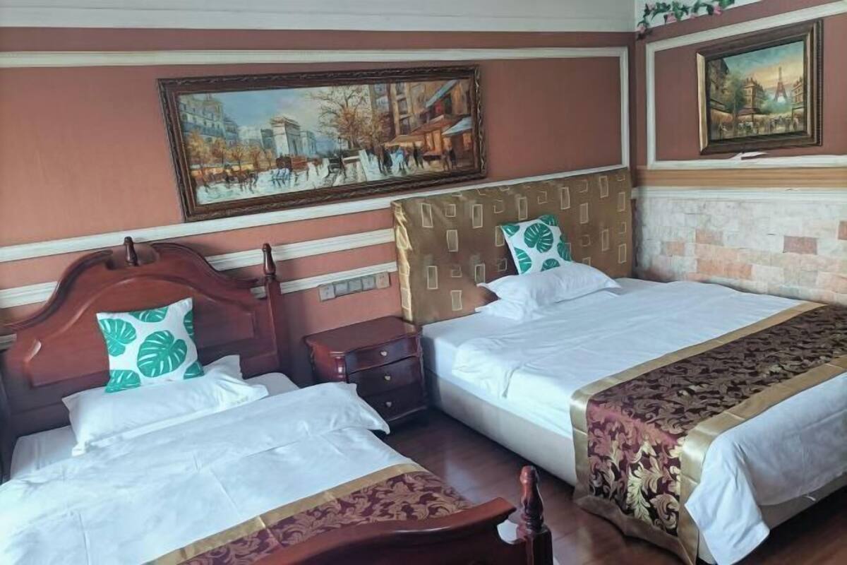 A hotel room with two beds, a wooden headboard, a nightstand, and a painting on the wall.