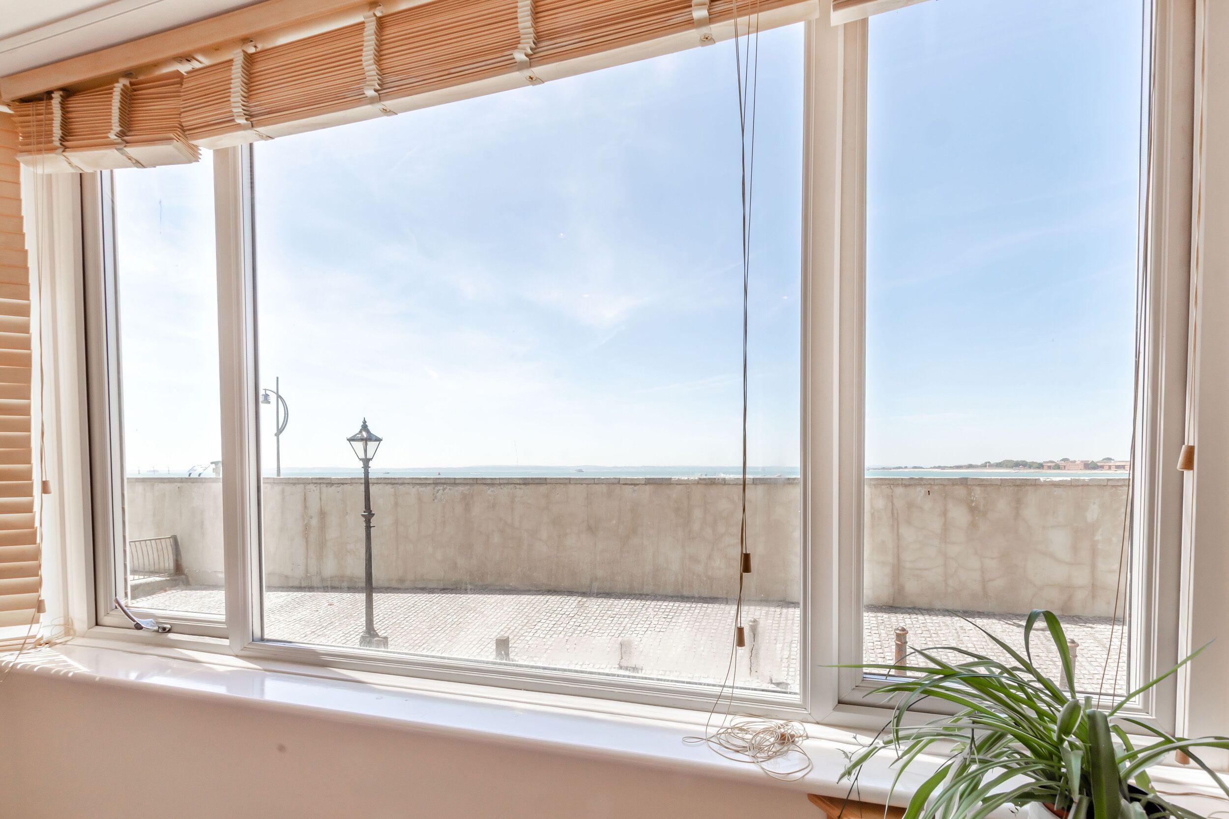 A room with a large window overlooking a rooftop area with a view of the sea.