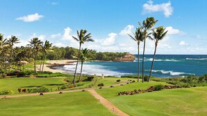 A golf course with a view of the ocean and palm trees. - Poipu Sands 522 Gorgeous Oceanfront  By Suite Paradise (Koloa)