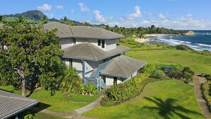 A two-story building with a covered porch and a view of the ocean. - Poipu Sands 522 Gorgeous Oceanfront  By Suite Paradise (Koloa)