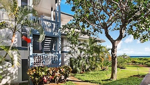 A hotel with a balcony, palm trees, and a view of the ocean. - Poipu Sands 522 Gorgeous Oceanfront  By Suite Paradise (Koloa)