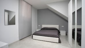 Une chambre à coucher moderne avec un lit, des tables de chevet, un miroir et un plafond en pente.