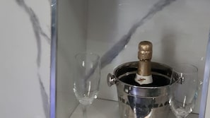 Metallinen astia, jonka päältä on kullankeltainen, kaksi tyhjää lasia ja taustalla marmorikuvioitu seinä.