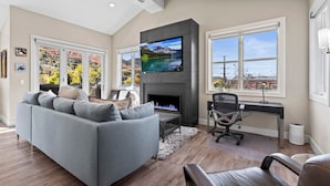 Una sala de estar moderna con chimenea, televisor grande y vista al lago.