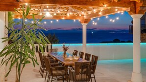 An outdoor dining area with a wooden pergola, string lights, and a view of the sea at dusk. - Seaview Villa MaToLi with heated 50sqm pool and 4 bedrooms, close to Split (Podstrana)