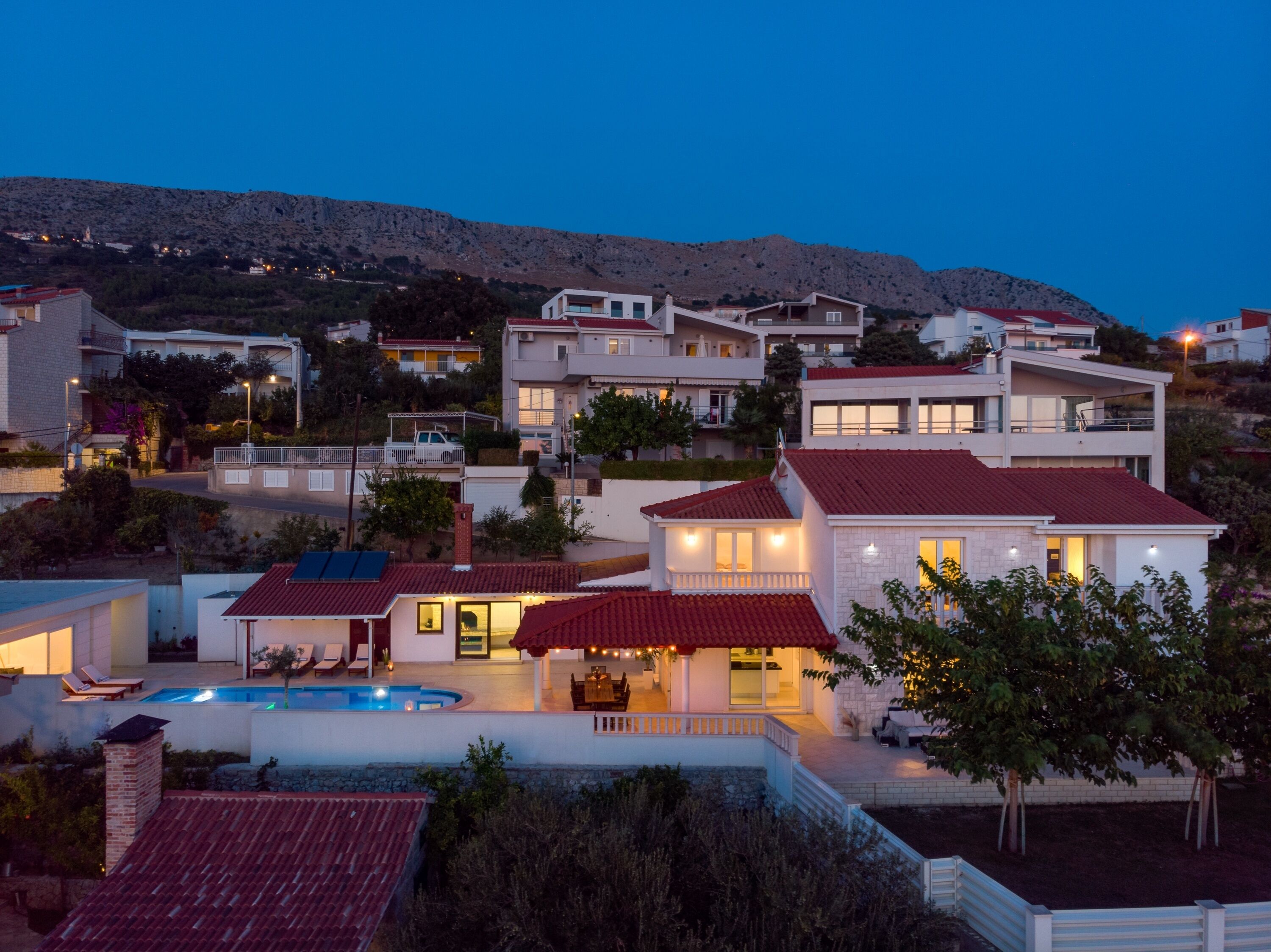 Una zona residencial con casas modernas, una piscina y una colina al fondo.