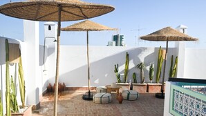 A rooftop terrace with potted cacti, woven umbrellas, and round cushions. - Riad Dar Rabiaa (Rabat)