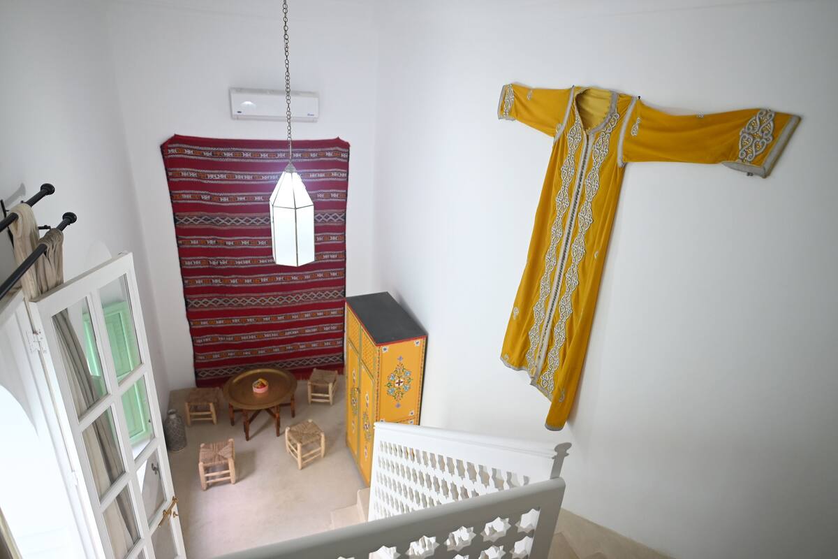 Una habitación con cama, una mesita, una silla, un armario y espacio para colgar ropa.