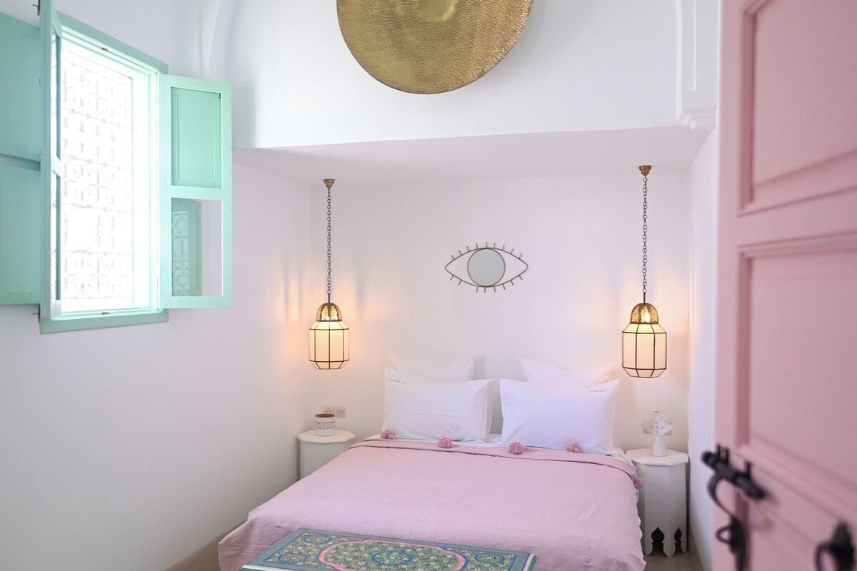 A bedroom with a bed, bedside tables, a decorative wall hanging, and a unique chest of drawers.