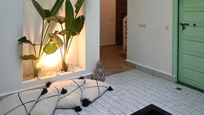 A hallway with white tiled flooring, green door, and a hanging light fixture. - Riad Dar Rabiaa (Rabat)