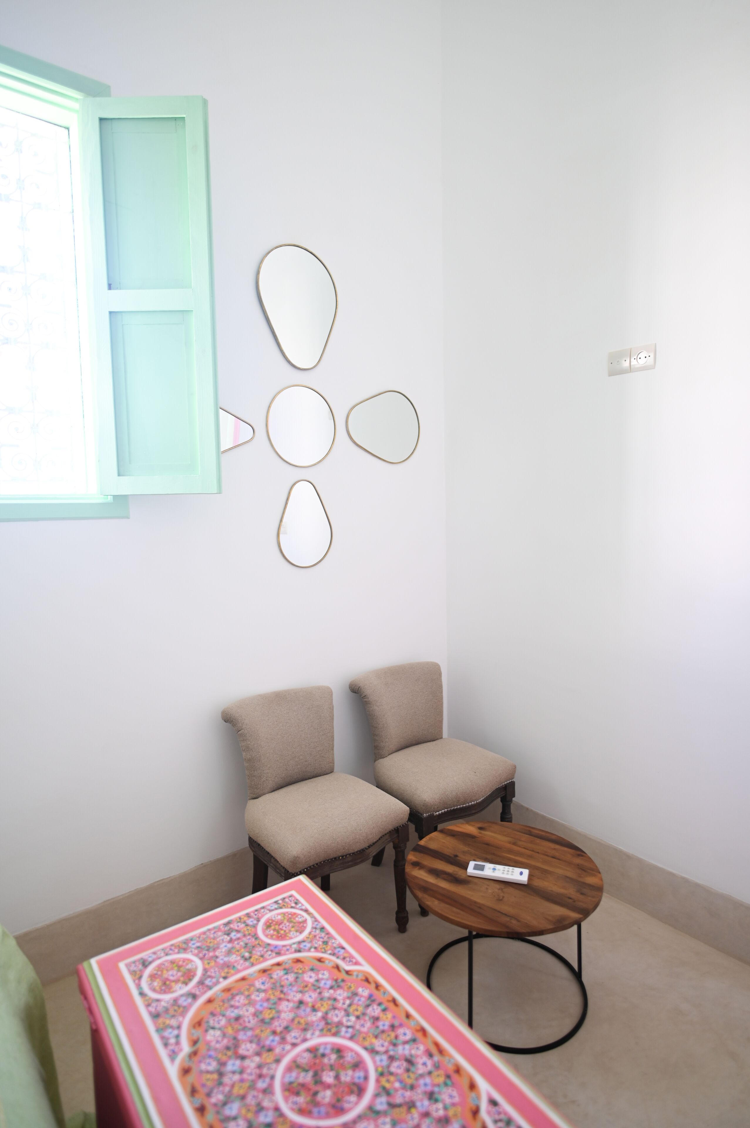 A room with two chairs, a small round table, and a wall-mounted decorative piece.