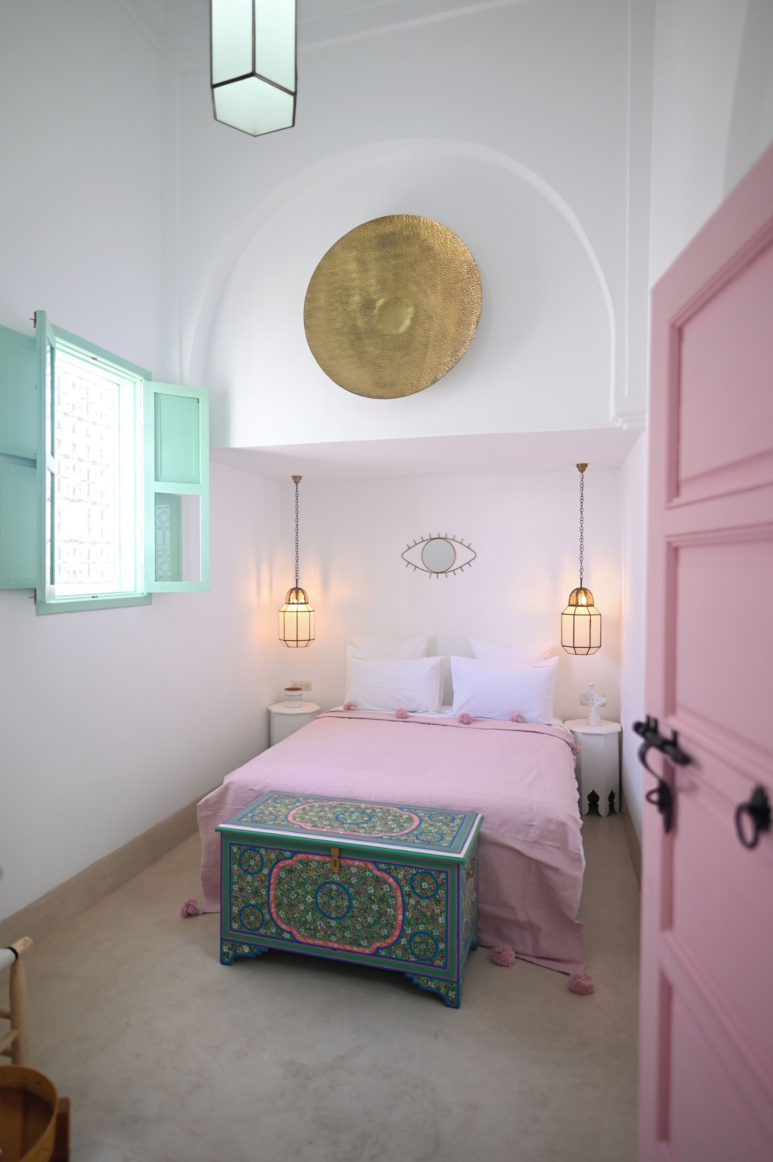 A bedroom with a bed, bedside tables, a decorative wall hanging, and a unique chest of drawers.