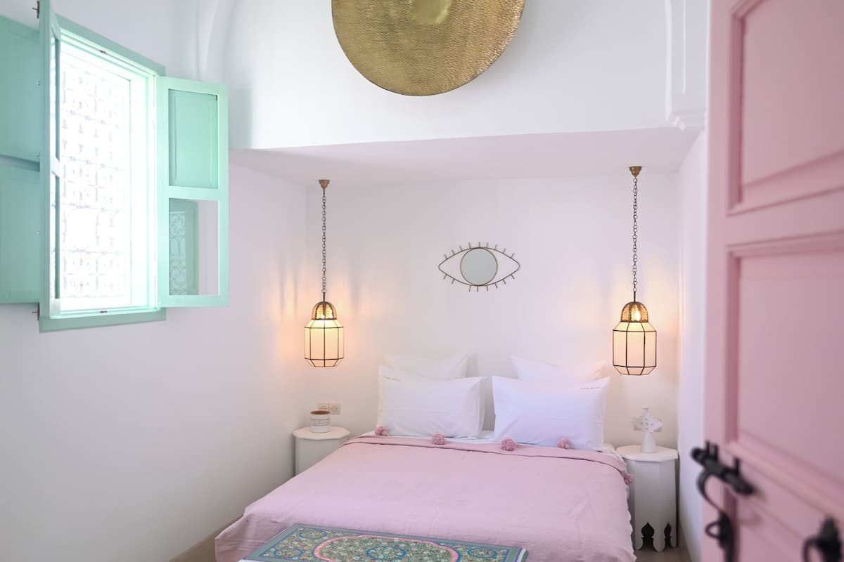 Un dormitorio con cama, mesitas de noche, un tapiz decorativo y un aparador singular.