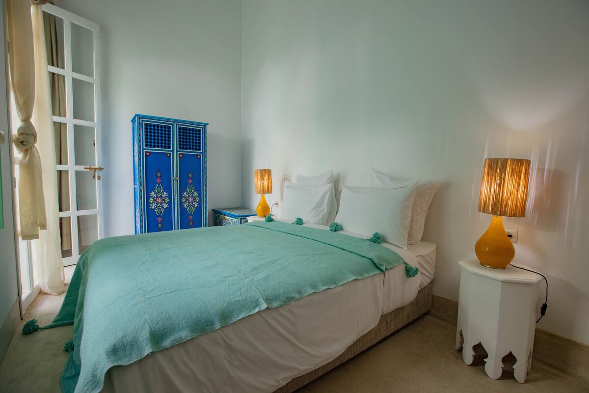 Un dormitorio con una cama, dos mesitas de noche, un armario y una puerta.