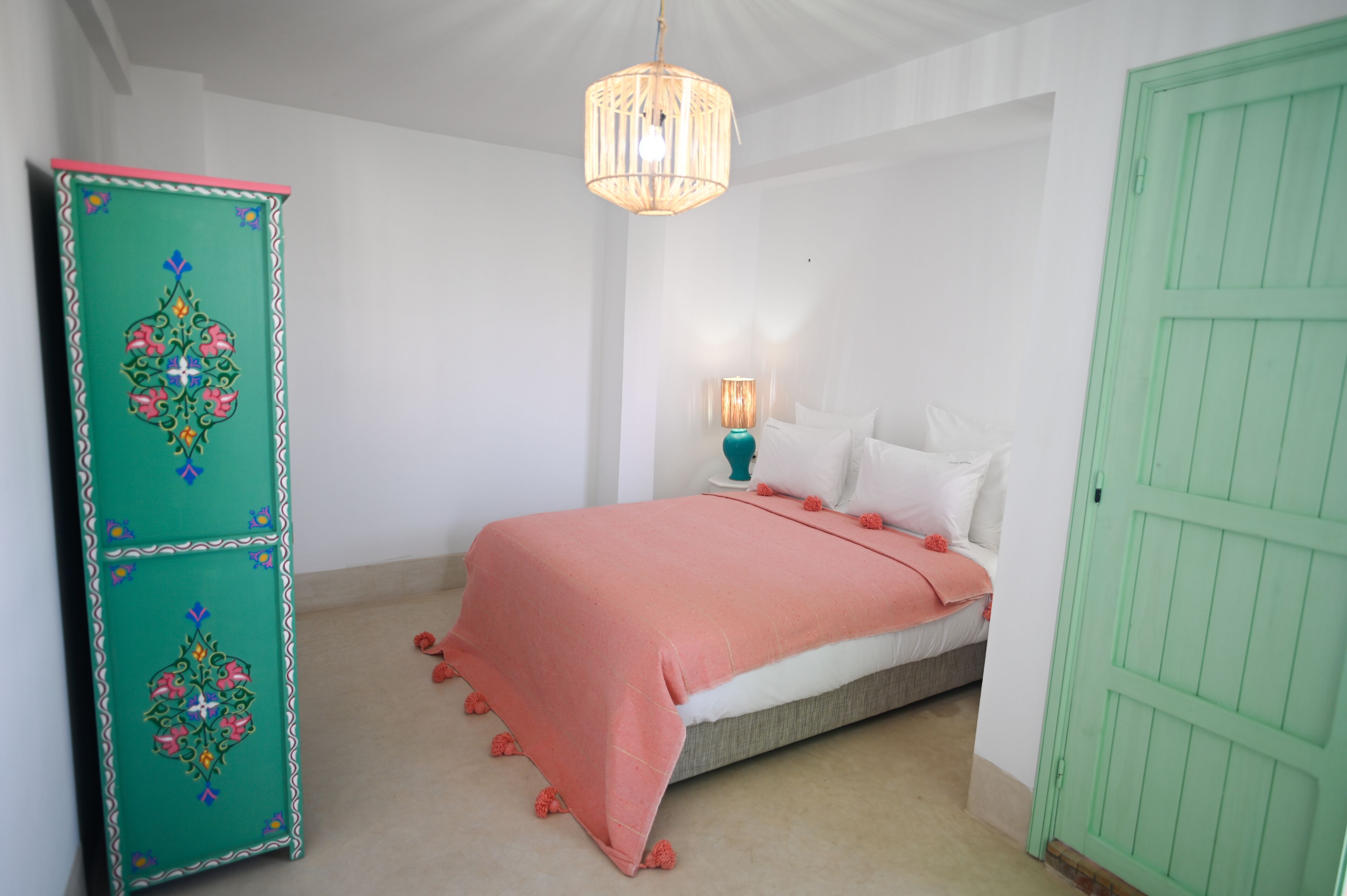 Un dormitorio con cama, un armario verde, una puerta verde y una lámpara colgante.