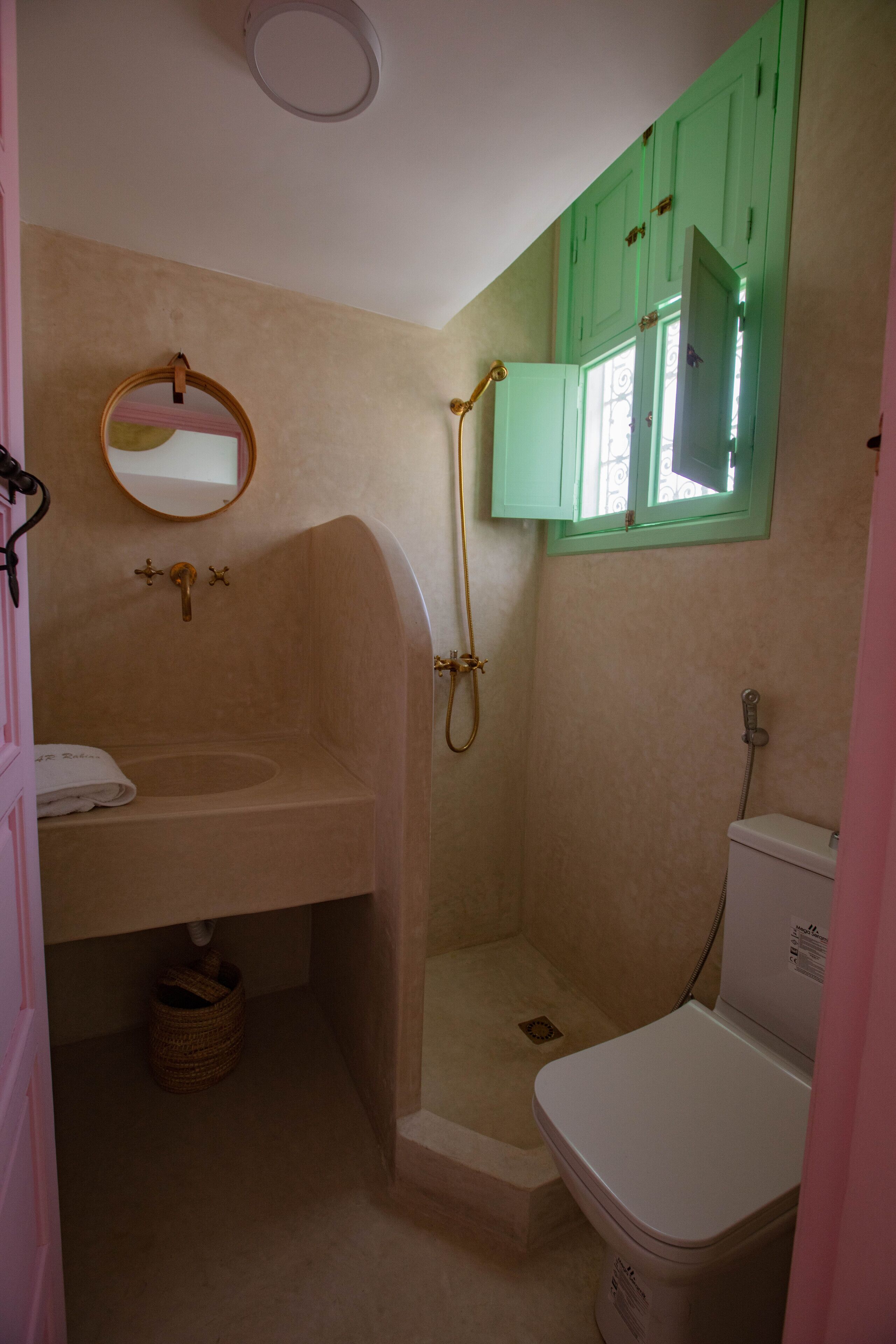 Baño con lavabo, espejo, ducha e inodoro.