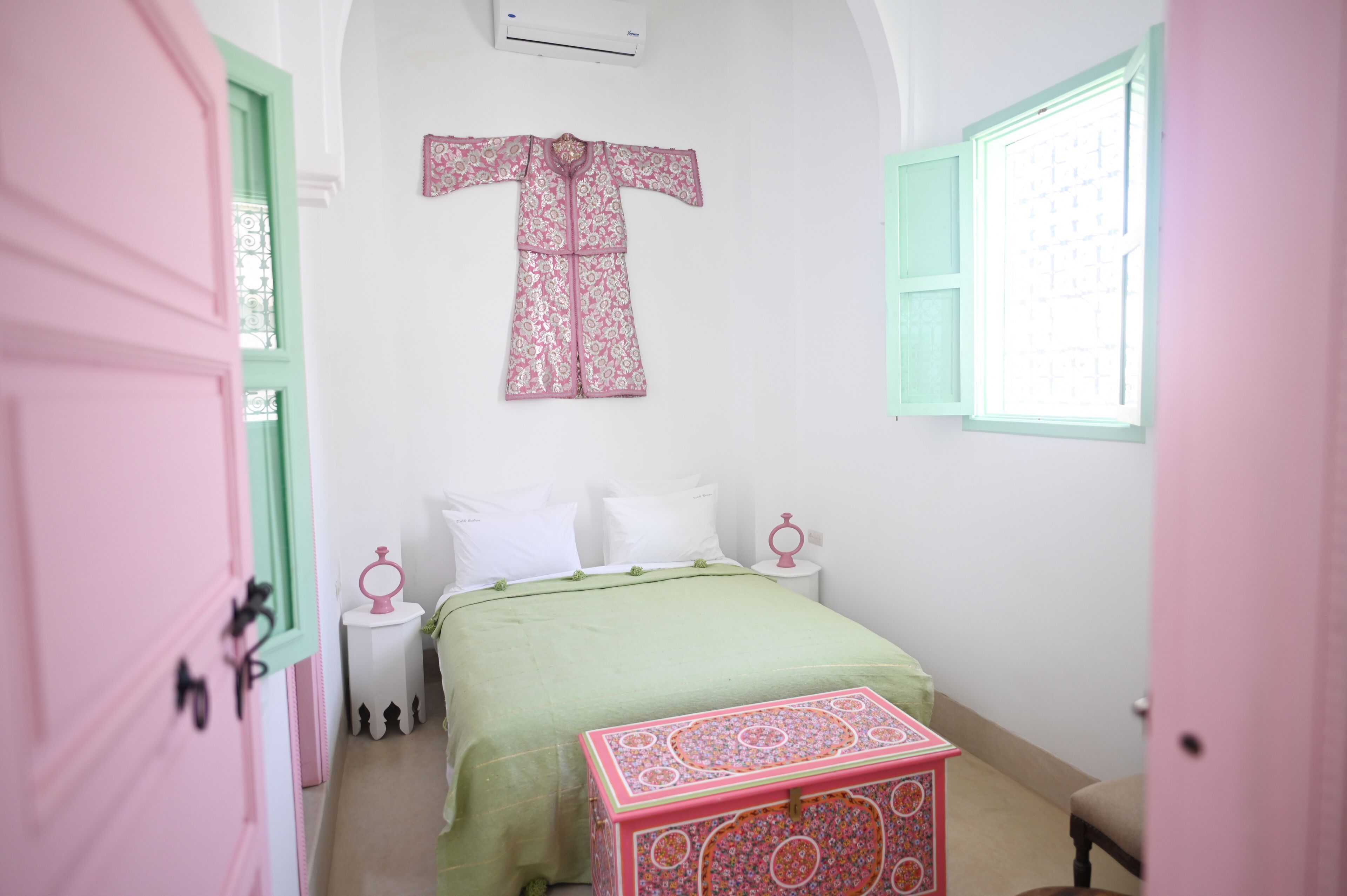 A bedroom with a bed, a nightstand, a dresser, a window, and a door.