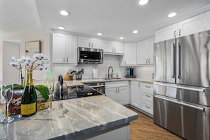 Una cocina moderna con armarios blancos, electrodomésticos de acero inoxidable y encimera de mármol.