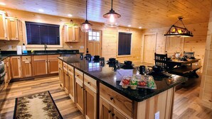 Une cuisine de style rustique, avec des meubles en bois, un plan de travail noir et un luminaire suspendu.