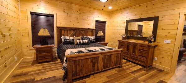 A wooden cabin bedroom with a bed, nightstands, a dresser, and a mirror. - Big Porch and Wide Open Spaces (Sevierville)
