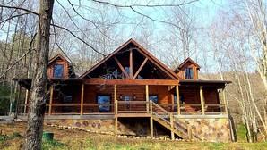 Une cabane en bois, avec des fondations en pierre, plusieurs balcons et un escalier menant aux niveaux supérieurs.