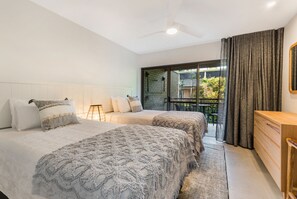 Une chambre avec deux lits, une table de chevet, une commode et une vue sur l’extérieur.