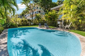 Piscina con bordi piastrellati, immersa nel verde e recintata.